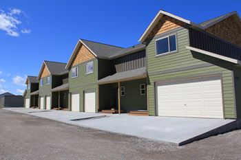 a row of green houses with white garage doors at Copper Pines, Bozeman, MT